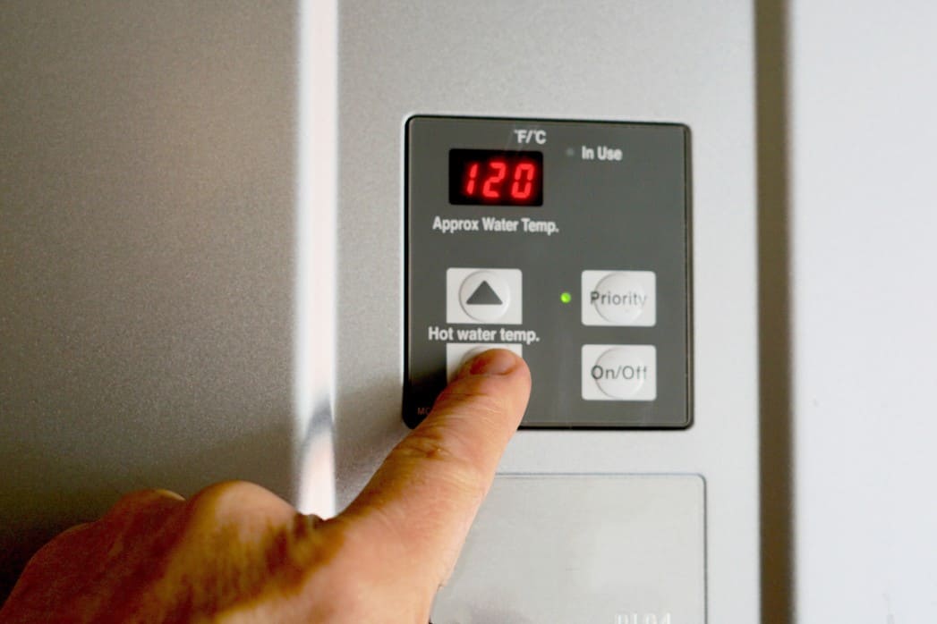 A close up finger changing the temperature on an electric water heater