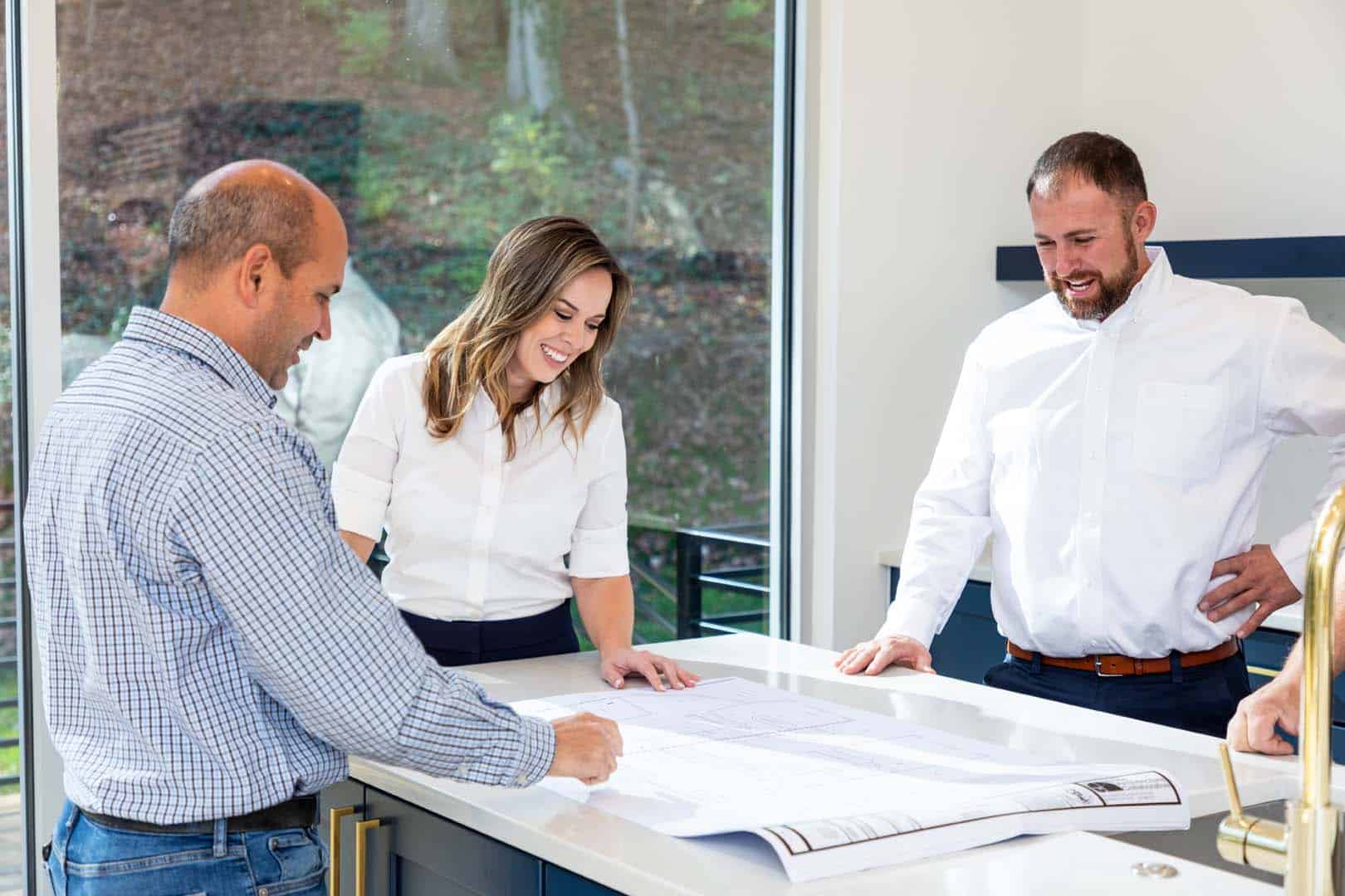 A client pointing at part of a blueprint with the Bio Plumbing owners looking at the blueprint